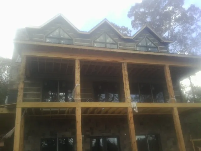 Dormers and porch framing on a large log home under construction — Roof Coating work by our crew in Yorkville