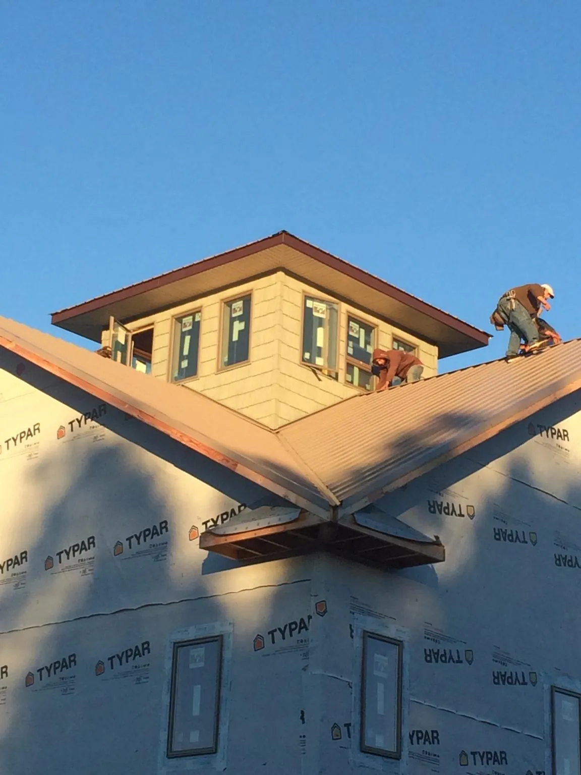 Roofers working around a rooftop cupola on a new metal roof at sunset — Roof Waterproofing in Yorkville by Roofing Brothers